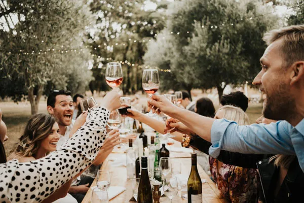 Wedding guests raising glasses for a toast at an outdoor reception.